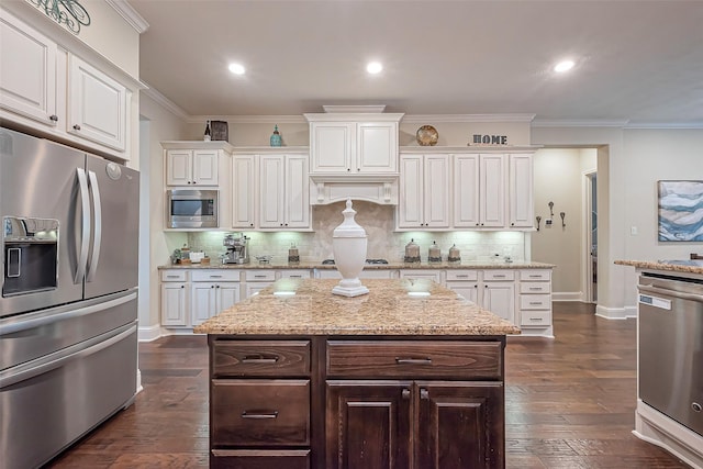 kitchen with dark wood finished floors, stainless steel appliances, backsplash, ornamental molding, and white cabinets