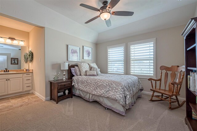 bedroom with lofted ceiling, ensuite bathroom, light carpet, a sink, and baseboards