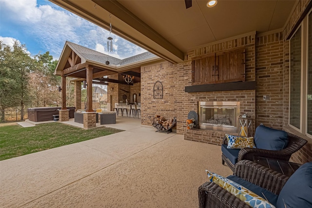 view of patio with an outdoor living space with a fireplace and a hot tub