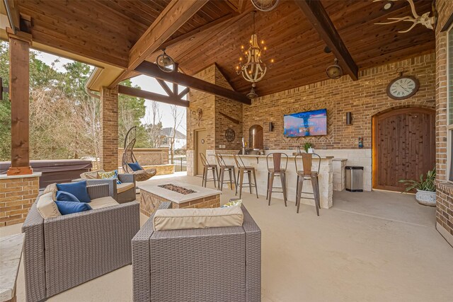 view of patio featuring a hot tub, outdoor dry bar, and an outdoor living space with a fire pit