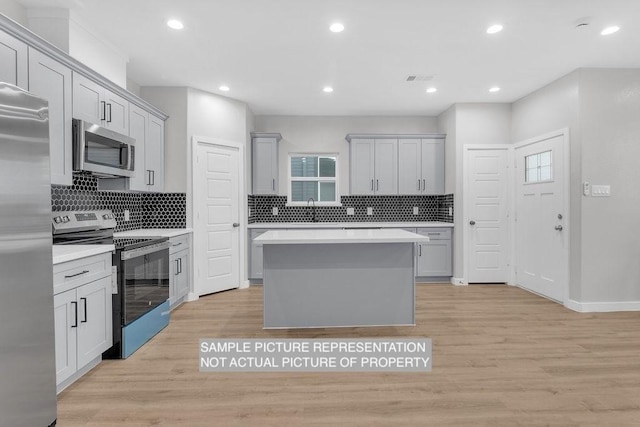 kitchen featuring gray cabinetry, light wood-type flooring, light countertops, stainless steel appliances, and a sink