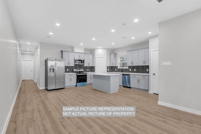 kitchen with a kitchen island, light countertops, decorative backsplash, light wood-style flooring, and stainless steel appliances