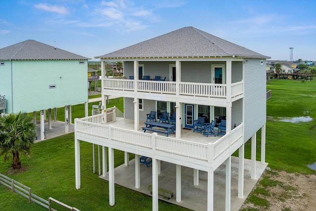 rear view of property with a patio area, a lawn, a balcony, and a shingled roof