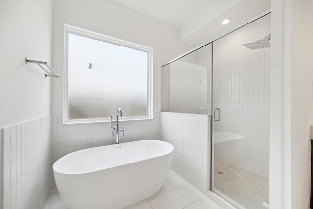 full bathroom featuring recessed lighting, a wainscoted wall, tile walls, a freestanding bath, and a shower stall