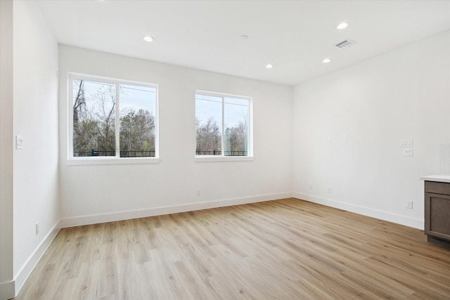 empty room with baseboards, light wood-type flooring, visible vents, and recessed lighting