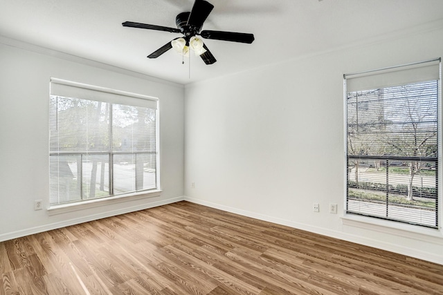 unfurnished room featuring ceiling fan, plenty of natural light, wood finished floors, and baseboards