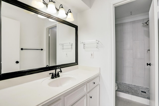 full bath featuring crown molding, a tile shower, vanity, and toilet