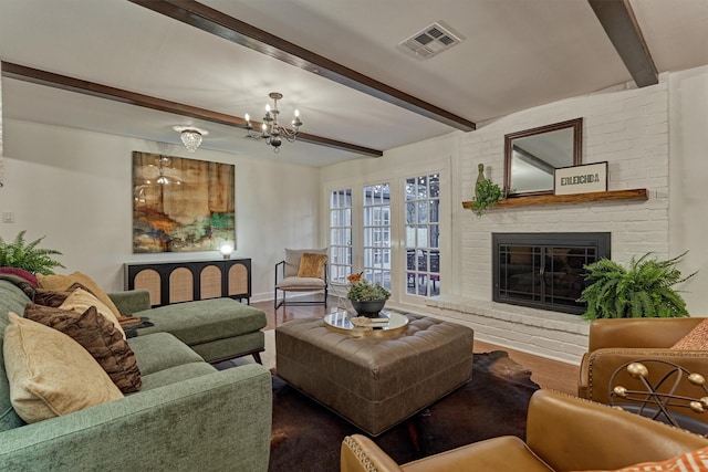 living area with beamed ceiling, a brick fireplace, wood finished floors, and visible vents