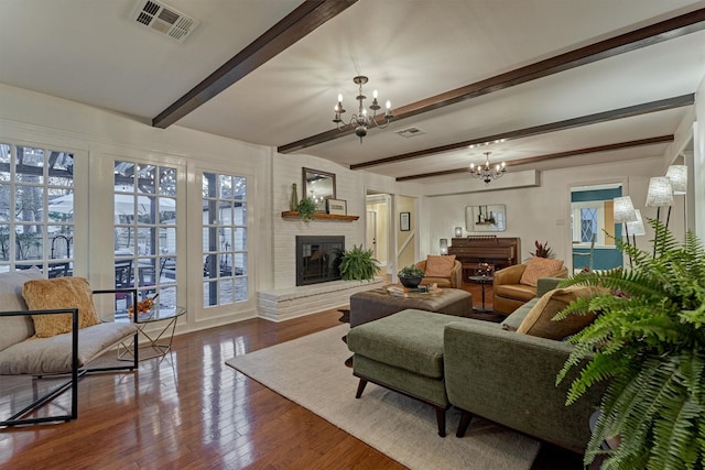 living area featuring beam ceiling, a fireplace, wood finished floors, and visible vents