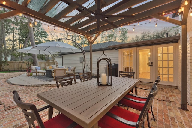 patio terrace at dusk featuring ceiling fan, fence, french doors, a pergola, and outdoor dining space