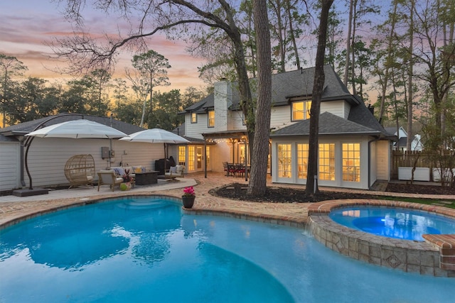 view of swimming pool with french doors, a patio, a pool with connected hot tub, an outdoor hangout area, and fence