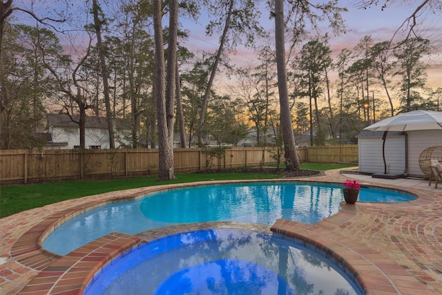 view of swimming pool featuring a patio, a fenced backyard, and a pool with connected hot tub