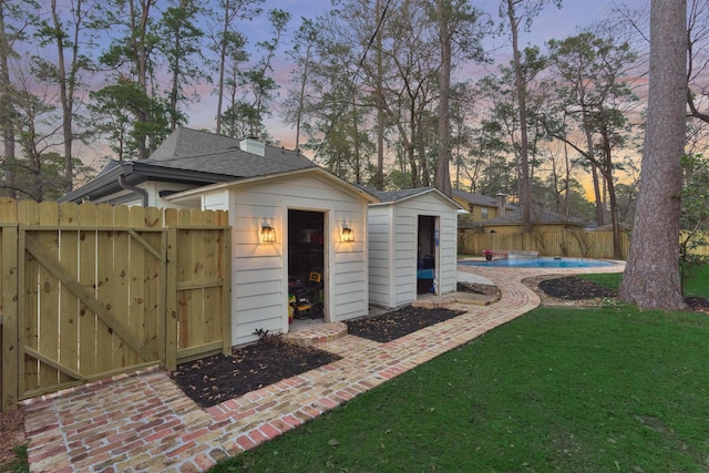 view of shed with a gate, fence, and a fenced in pool