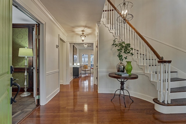 entrance foyer featuring crown molding, stairway, an inviting chandelier, wood finished floors, and baseboards