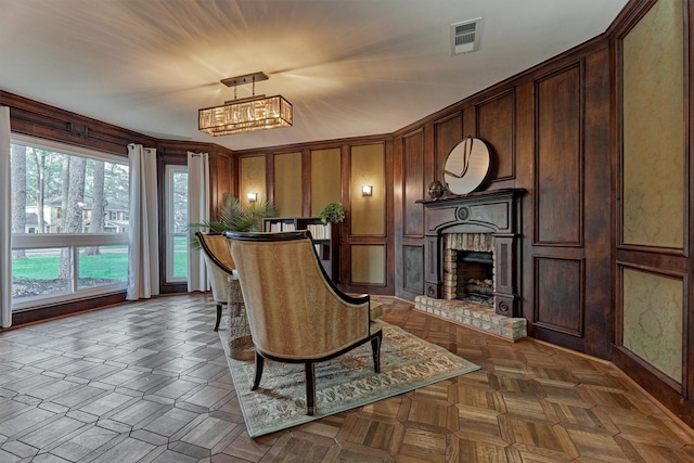 living area with visible vents, a decorative wall, a fireplace, and an inviting chandelier