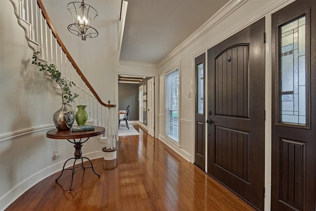 entryway featuring stairs, hardwood / wood-style floors, an inviting chandelier, and crown molding