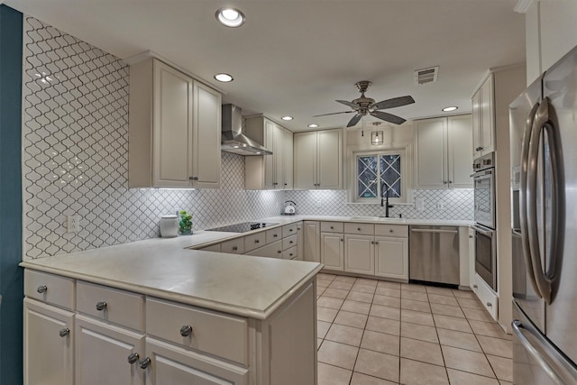 kitchen featuring visible vents, appliances with stainless steel finishes, wall chimney range hood, backsplash, and light tile patterned flooring