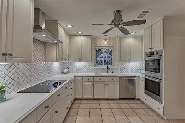 kitchen with a sink, visible vents, light countertops, appliances with stainless steel finishes, and wall chimney range hood