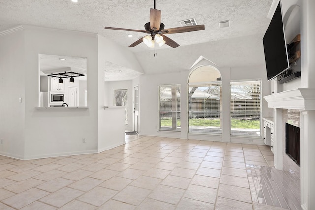 unfurnished living room featuring visible vents, a ceiling fan, vaulted ceiling, a textured ceiling, and a tile fireplace