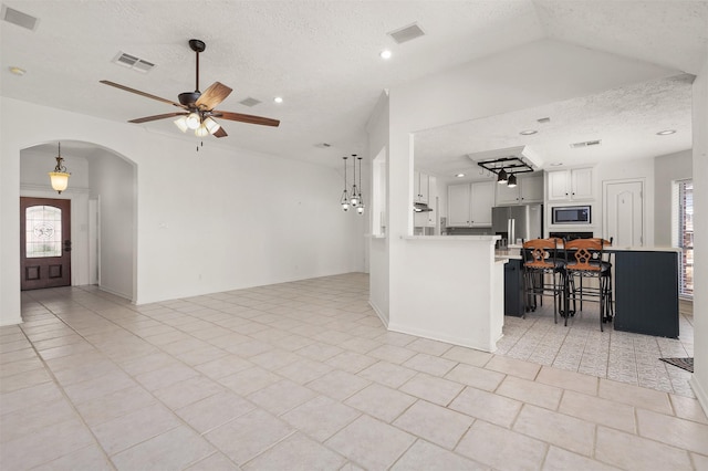 kitchen featuring arched walkways, light countertops, visible vents, appliances with stainless steel finishes, and a kitchen bar