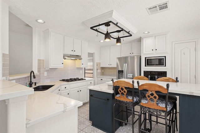 kitchen featuring visible vents, under cabinet range hood, black appliances, white cabinetry, and a sink