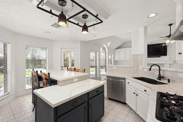 kitchen featuring decorative backsplash, a center island, stainless steel dishwasher, white cabinetry, and a sink