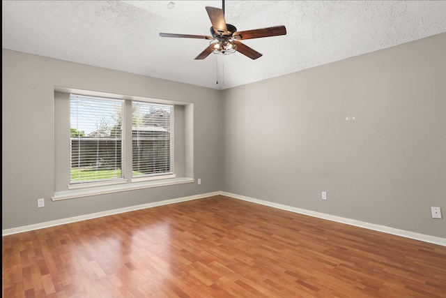 unfurnished room featuring baseboards, light wood-style flooring, ceiling fan, vaulted ceiling, and a textured ceiling