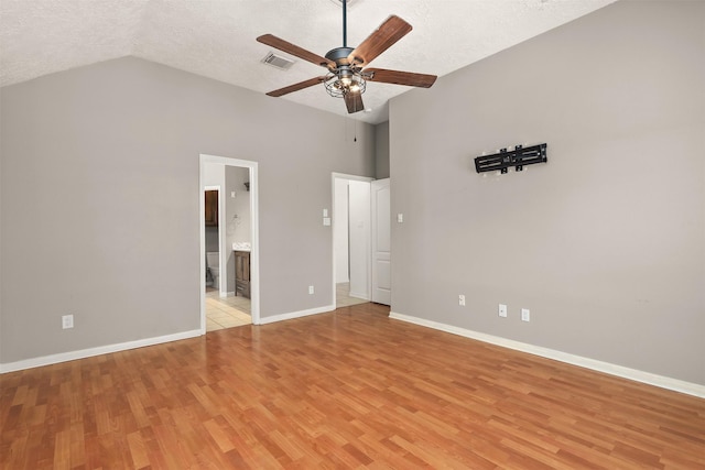 unfurnished bedroom featuring lofted ceiling, a textured ceiling, light wood-type flooring, and baseboards