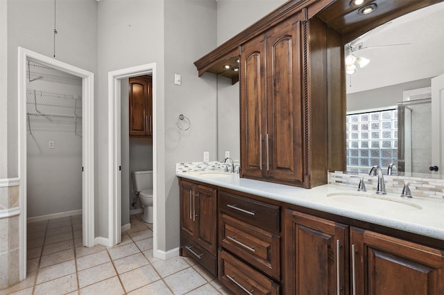 full bathroom with baseboards, a sink, toilet, and double vanity