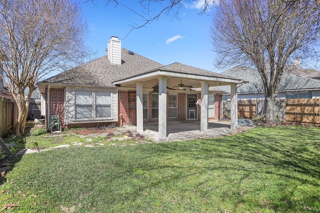 rear view of property featuring a yard, brick siding, a fenced backyard, and a ceiling fan