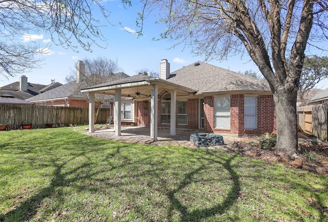 rear view of house featuring a patio, ceiling fan, a fenced backyard, a yard, and brick siding