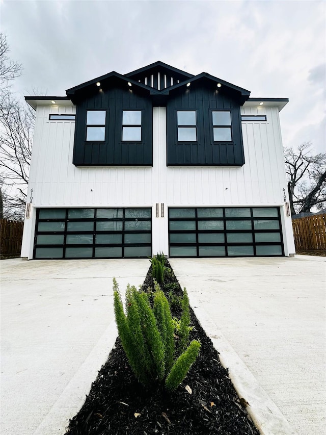 modern farmhouse style home featuring a garage, concrete driveway, board and batten siding, and fence