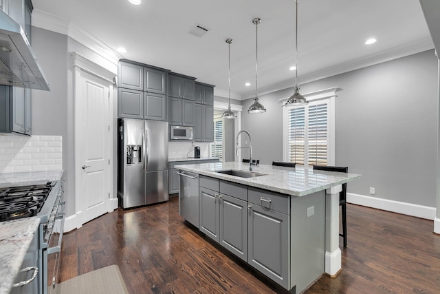 kitchen with appliances with stainless steel finishes, crown molding, gray cabinetry, wall chimney range hood, and a sink