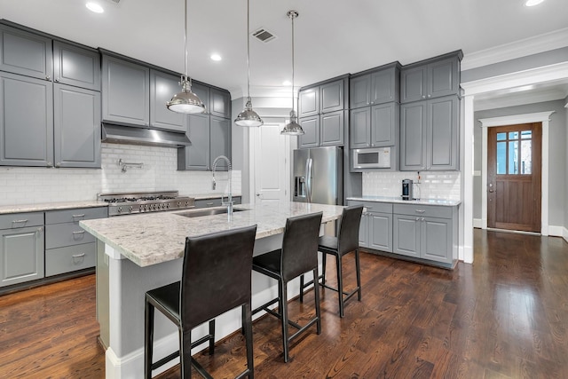 kitchen featuring stainless steel fridge, white microwave, gray cabinets, under cabinet range hood, and a sink