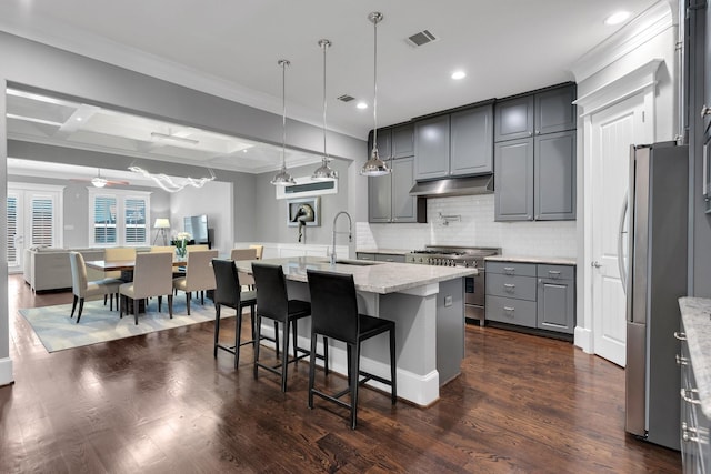 kitchen with dark wood-style flooring, stainless steel appliances, gray cabinetry, under cabinet range hood, and a sink