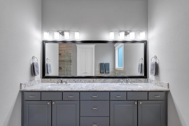 full bath with a sink, a shower stall, and double vanity