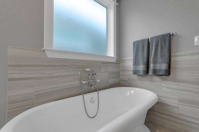 full bathroom with a freestanding tub and tile walls