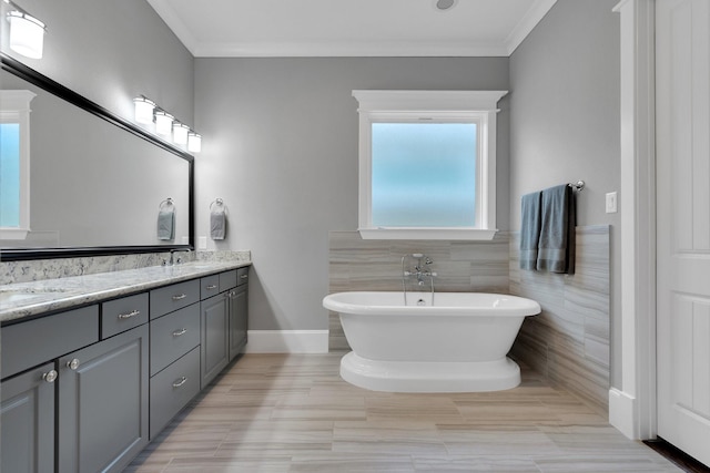 full bathroom featuring a sink, double vanity, ornamental molding, and a freestanding tub