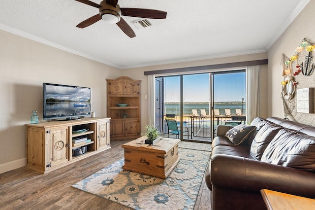 living room with ceiling fan, wood finished floors, visible vents, baseboards, and ornamental molding