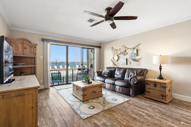 living area featuring light wood-style flooring, a textured ceiling, visible vents, and crown molding