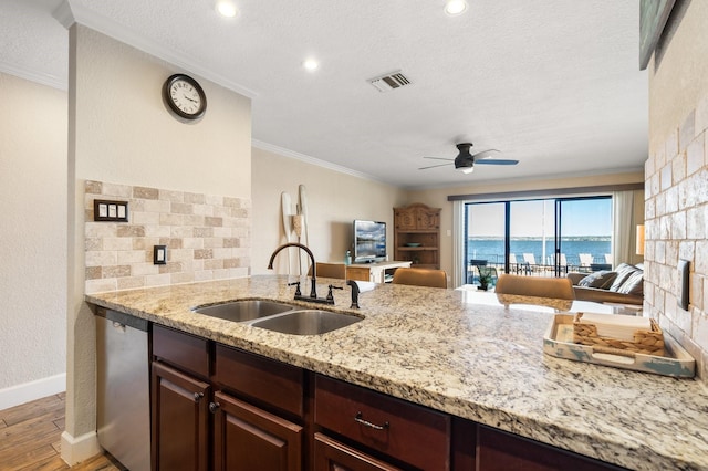 kitchen with a sink, ornamental molding, stainless steel dishwasher, light stone countertops, and light wood finished floors