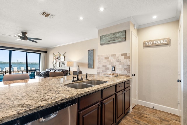 kitchen featuring a sink, visible vents, ornamental molding, stainless steel dishwasher, and light stone countertops