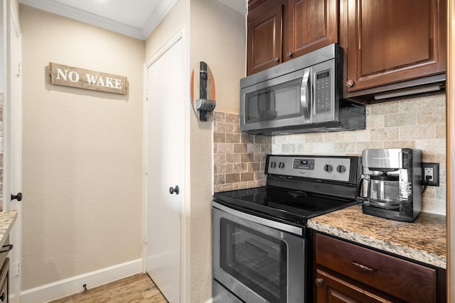 kitchen with light wood finished floors, stainless steel appliances, backsplash, ornamental molding, and baseboards