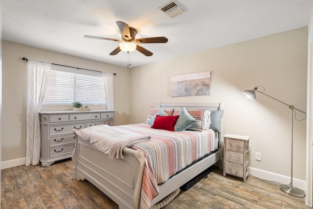 bedroom with wood finished floors, visible vents, and baseboards