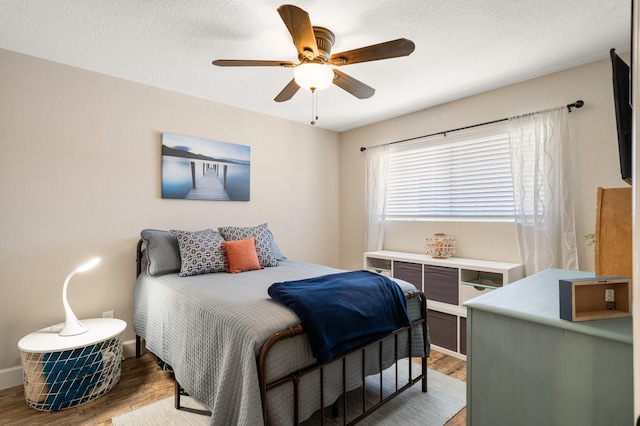 bedroom with a textured ceiling, light wood-style flooring, and a ceiling fan