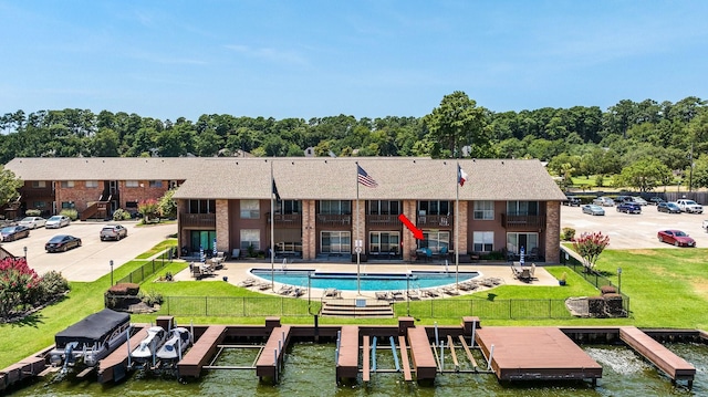 rear view of property with a lawn, a patio area, boat lift, and a fenced backyard