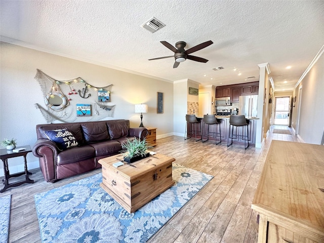 living area with visible vents, crown molding, and light wood finished floors