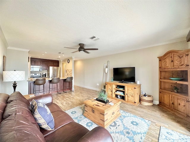 living room with visible vents, a ceiling fan, crown molding, a textured ceiling, and light wood-type flooring