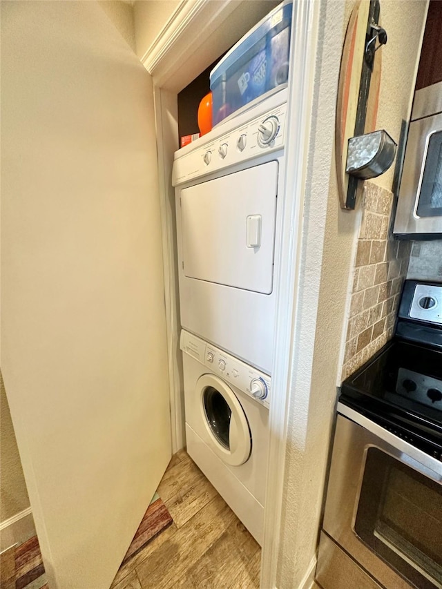 laundry area featuring stacked washing maching and dryer, laundry area, and light wood-style floors