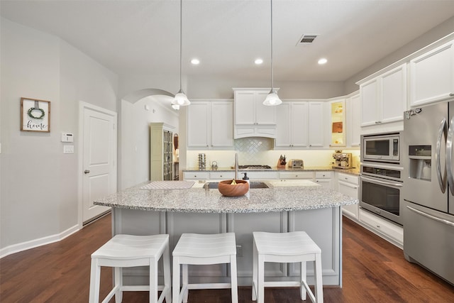 kitchen featuring stainless steel appliances, arched walkways, white cabinets, and dark wood finished floors